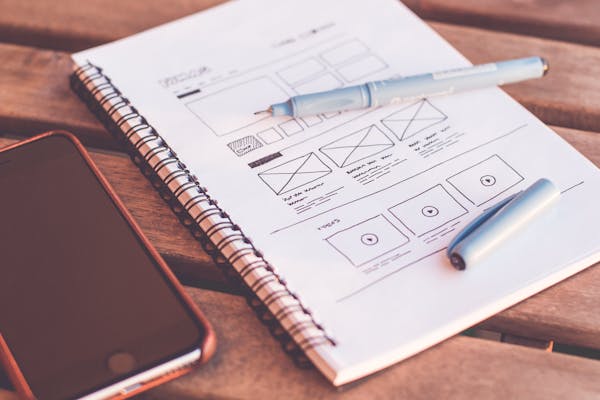 Website wireframe sketches on notebook with phone